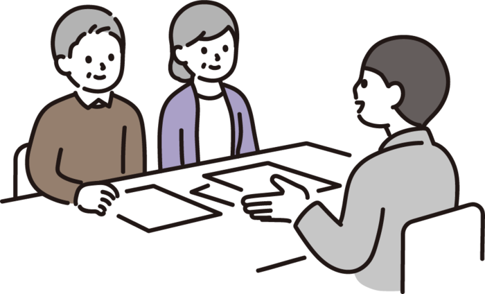 一人の男性が二人の男女へ机の座りながら、何かを提案している様子